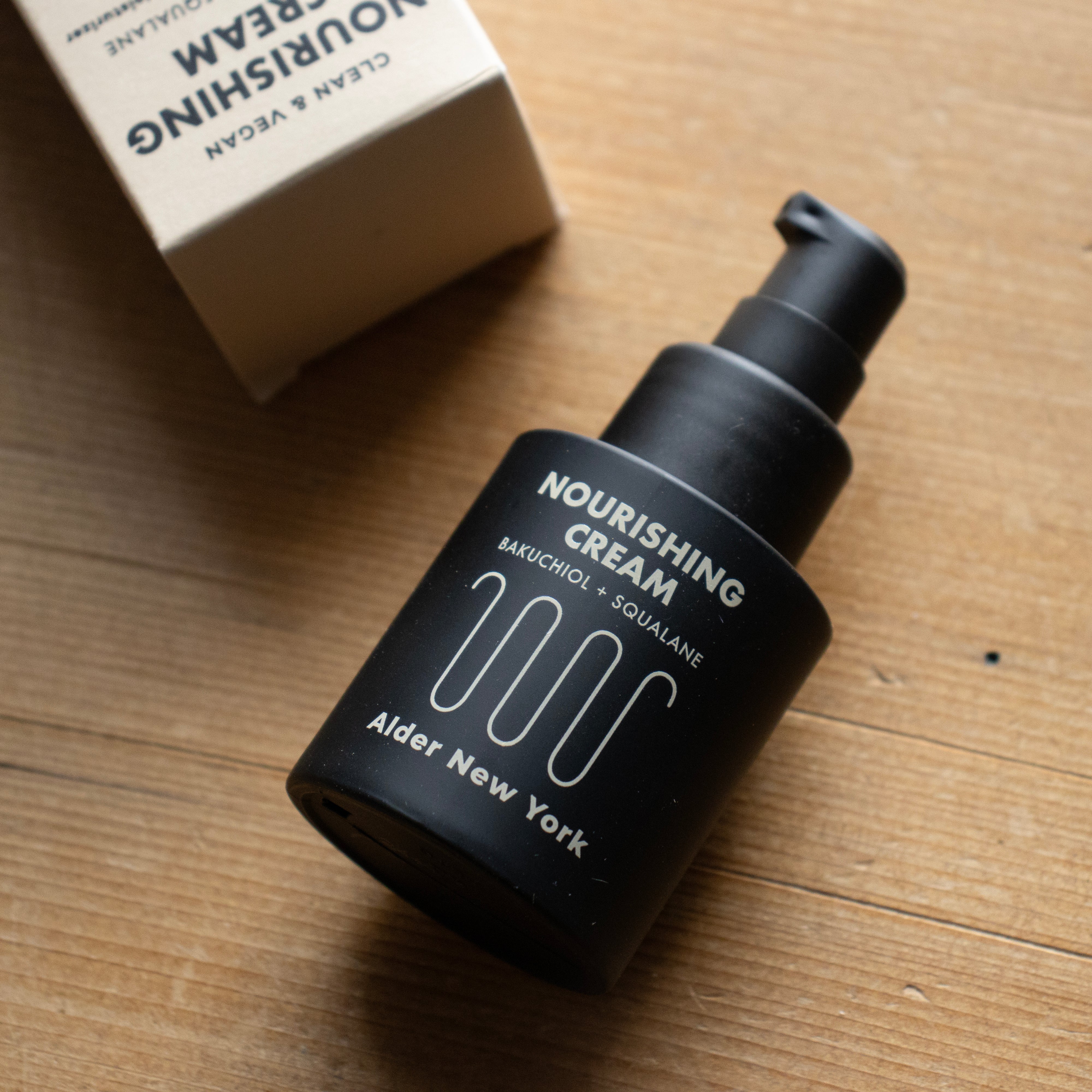 A Bottle of Alder New York Nourishing Cream on a wood surface